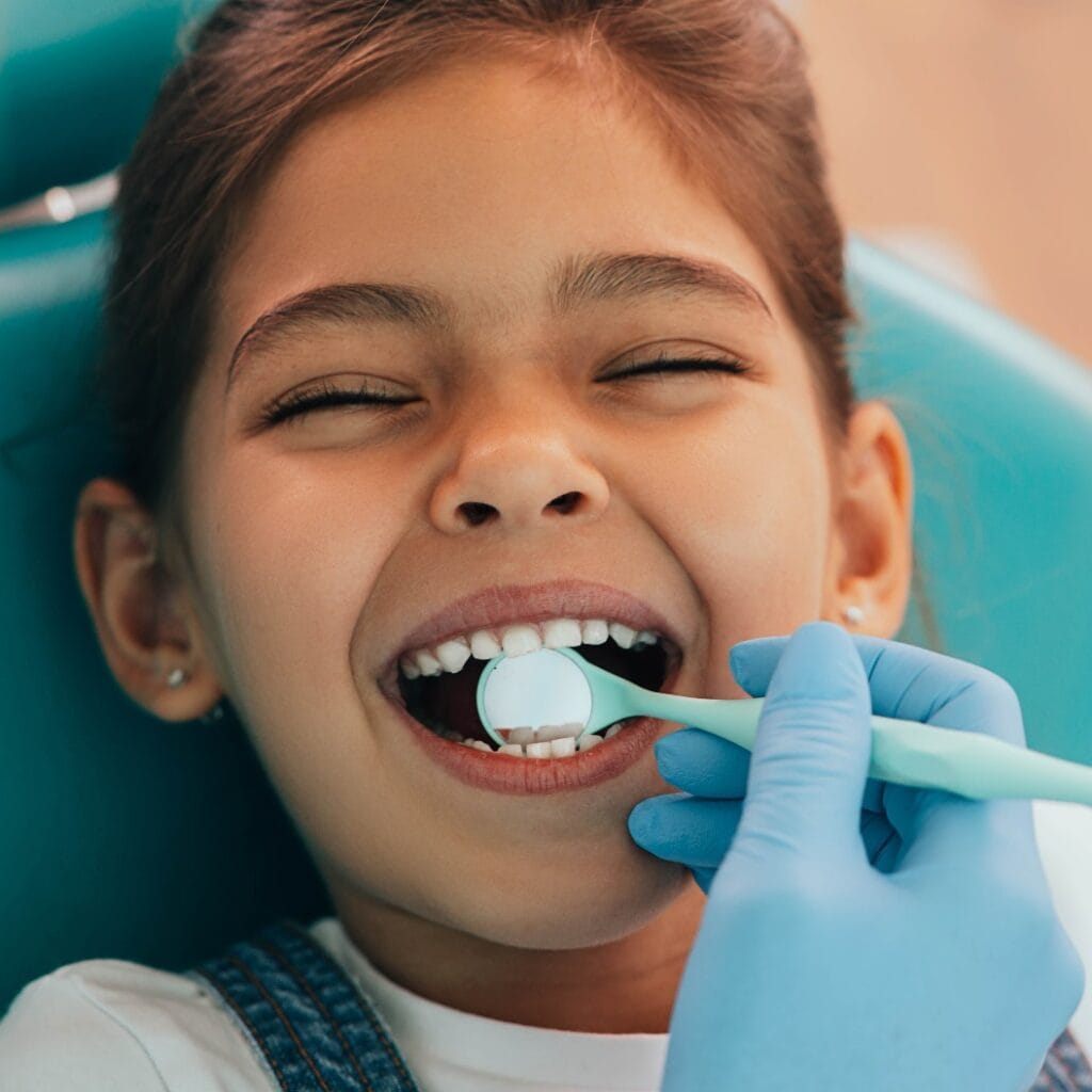 Cute little girl getting teeth exam at dental clinic